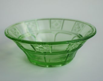 May include: A green glass bowl with a geometric pattern. The bowl is made of clear glass with a green tint.