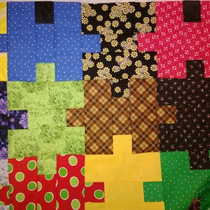 Puede incluir: Un edred&oacute;n de retazos en progreso, con una variedad de telas coloridas. Los bloques del edred&oacute;n est&aacute;n dispuestos en un patr&oacute;n de cuadr&iacute;cula, cada bloque compuesto por m&uacute;ltiples piezas de tela. Las telas incluyen patrones florales, de lunares y a cuadros.