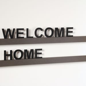 May include: Two brown wooden shelves with the words "WELCOME" and "HOME" in black letters.
