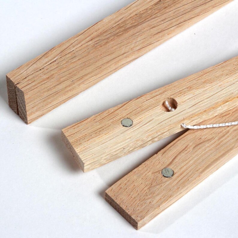 May include: Three wooden dowels with magnets and a white string attached. The dowels are used to create a hanging picture frame.