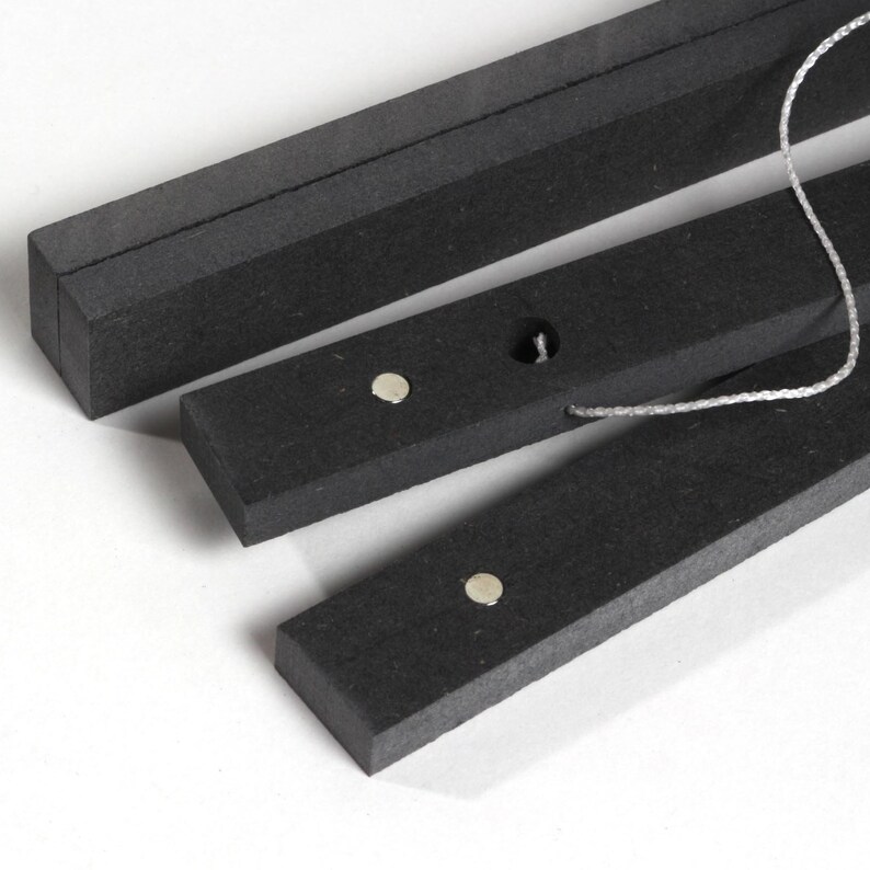 May include: Three black wooden rods with a string connecting them. Each rod has a small silver magnet on the top.