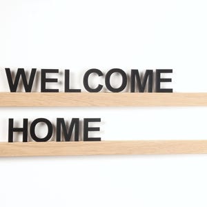 May include: Two wooden shelves with the words "WELCOME" and "HOME" in black letters.