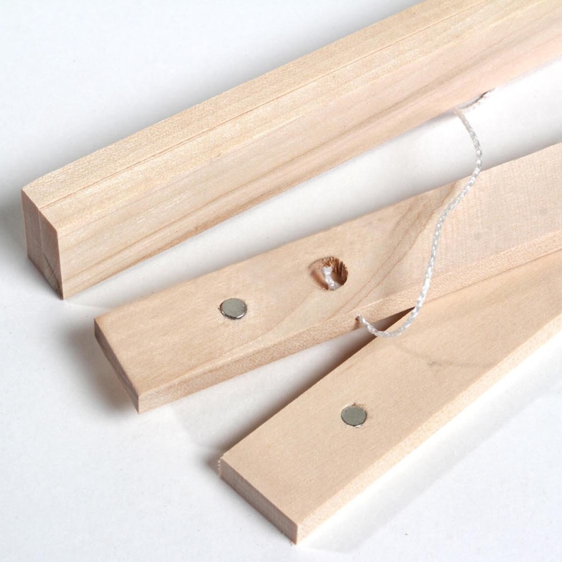 May include: Three wooden picture frame bars with metal magnets and a white string attached. The bars are made of natural wood and have a smooth finish.