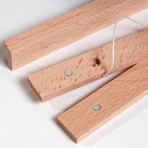 May include: Three wooden strips with magnets and a hole for string. The strips are light brown and have a smooth finish.