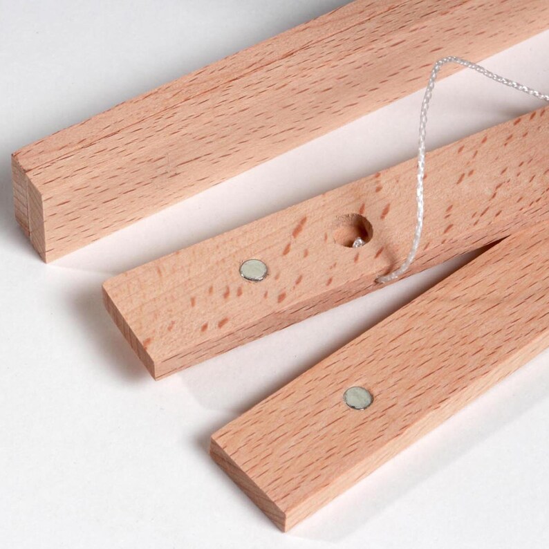 May include: Three wooden strips with magnets and a hole for string. The strips are light brown and have a smooth finish.