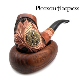 May include: A wooden smoking pipe with a carved wolf design and a black stem. The pipe is resting in a wooden stand.