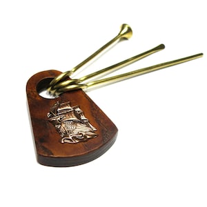 May include: A set of three brass smoking pipes with wooden handles. The handles are decorated with a ship design.