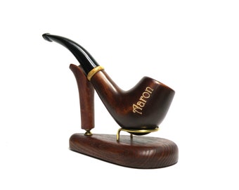 Op de afbeelding: Een donkerbruine houten pijp met een zwarte steel en een gouden band. De pijp is gegraveerd met de naam "Naron" en wordt getoond op een houten standaard.