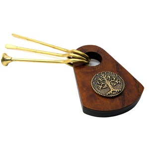 May include: A wooden smoking pipe holder with a brass tree design. The holder has three brass pipes attached to it.