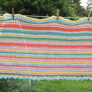 May include: A crocheted throw blanket with a striped pattern in shades of pink, yellow, blue, and green. The blanket has a scalloped edge.