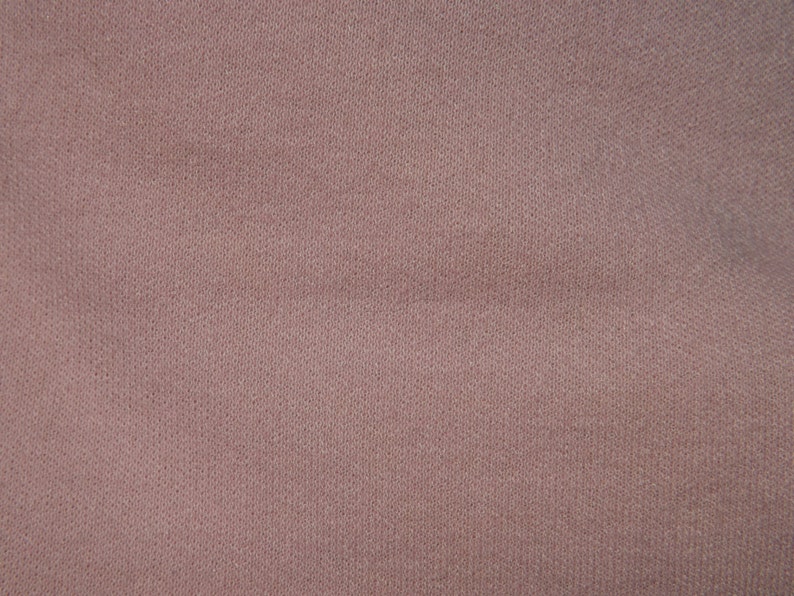 Puede incluir: Primer plano de una tela lisa de color marr&oacute;n claro con una textura sutil. La tela tiene un aspecto ligeramente granulado.