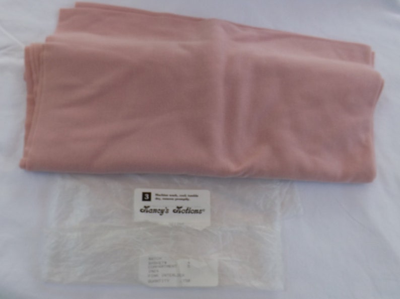 Puede incluir: Una muestra de tela rosa p&aacute;lido con una etiqueta blanca que dice "Fancy's Notions".