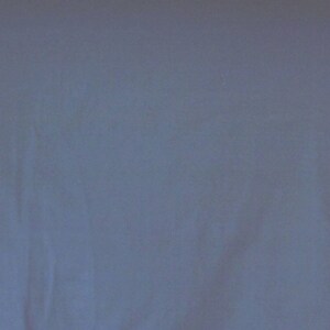 May include: Solid light blue fabric background. The fabric has a soft, slightly textured appearance. The color is a muted, cool tone, suitable for various applications.