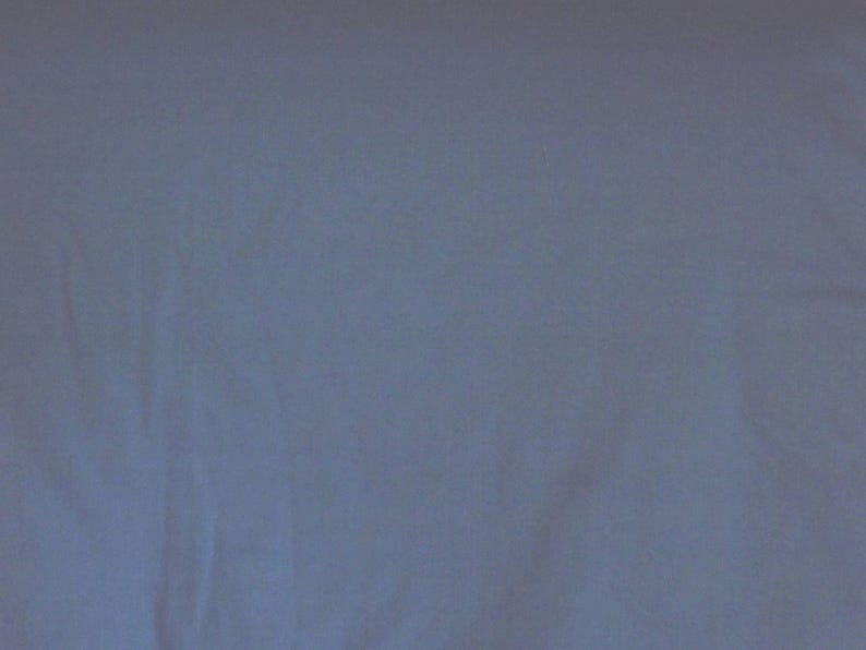 May include: Solid light blue fabric background. The fabric has a soft, slightly textured appearance. The color is a muted, cool tone, suitable for various applications.