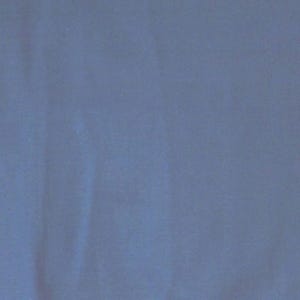 May include: Solid blue fabric with subtle texture and folds. The color is a muted, dusty blue, creating a soft and calming visual effect. The fabric appears to be a medium weight material, suitable for various applications.
