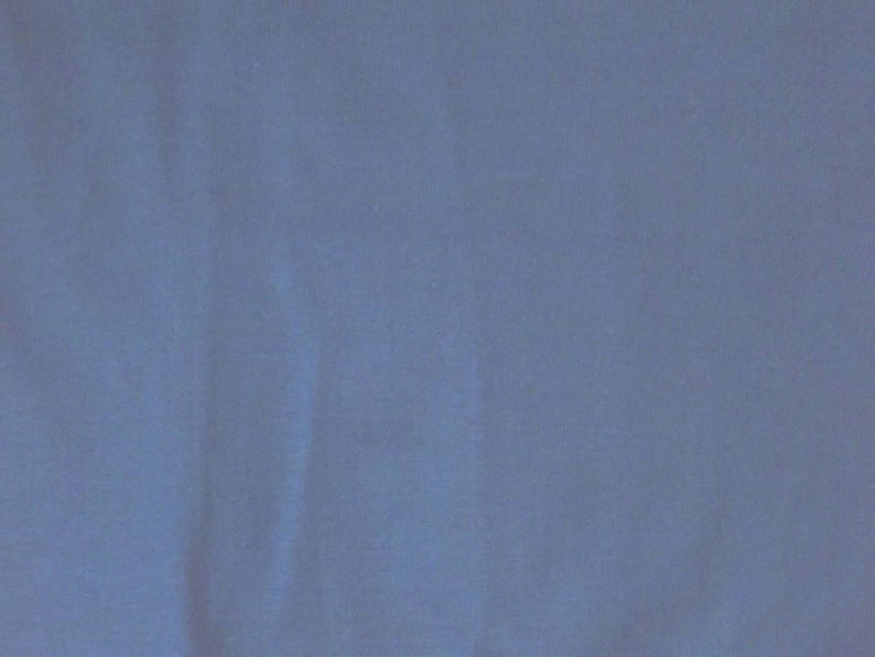 May include: Solid blue fabric with subtle texture and folds. The color is a muted, dusty blue, creating a soft and calming visual effect. The fabric appears to be a medium weight material, suitable for various applications.