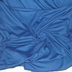 May include: A close-up shot of a deep blue fabric with soft folds and a subtle sheen. The fabric is draped over a white surface, creating a contrast. The texture appears smooth and flowing, suggesting a lightweight material.