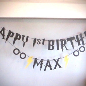 May include: Black and yellow Harry Potter themed birthday banner with the text "Happy 1st Birthday Max".