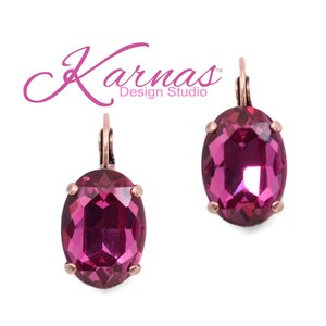 May include: A pair of pink oval-shaped earrings with a rose gold finish. The earrings feature a large, faceted crystal in the centre.