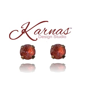 May include: A pair of small, round, red gemstone earrings with gold settings. The earrings are set against a white background.
