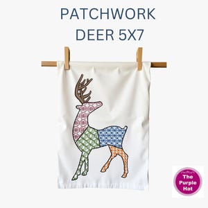 May include: A white fabric towel featuring an embroidered patchwork deer design with brown antlers and body sections in red, green, blue, and orange geometric patterns. The text PATCHWORK DEER 5X7 is printed above, and a purple logo reads The Purple Hat.