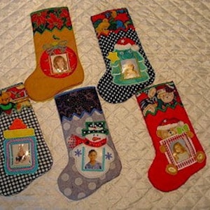 May include: Five Christmas stockings with various designs. Each stocking features a photo frame. The stockings have different colors, including yellow, red, black, and blue. The designs include a snowman, a Christmas tree, and other festive elements.