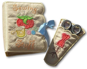 May include: A beige quilted fabric needle book with the embroidered text Sewing Stuff, a red tomato pincushion, and a yellow spool of thread, tied with a light blue ribbon, alongside a matching beige fabric scissor sheath with a red dress form.