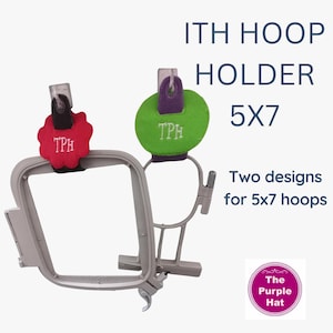 May include: Two embroidery hoop holders for 12.7 x 17.8 cm hoops. One holder has a red, scalloped top with "TPH" embroidered in white. The other has a green, oval top with "TPH" embroidered in white. The text "ITH HOOP HOLDER 5X7" is displayed.
