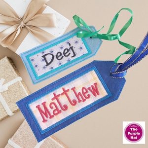Peut inclure: Deux étiquettes cadeaux personnalisées avec des noms brodés. L'une est bleu clair avec "Deef", l'autre bleu foncé avec "Matthew". Les deux ont des bordures décoratives et des rubans, pour les cadeaux.