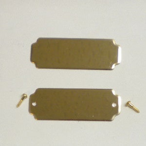 May include: Two gold-colored metal nameplates with rounded edges and two small screws.