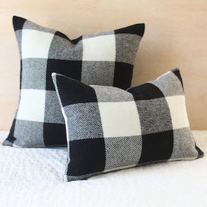 May include: Two black and white checkered throw pillows. The larger pillow is behind the smaller pillow.