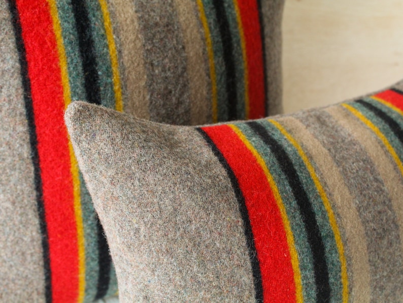 May include: Two striped throw pillows with a brown, red, yellow, blue and black pattern. The pillows are made of a soft, fuzzy material.