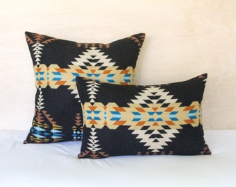 May include: Two decorative throw pillows with a black background and a geometric pattern in shades of brown, blue, and beige.