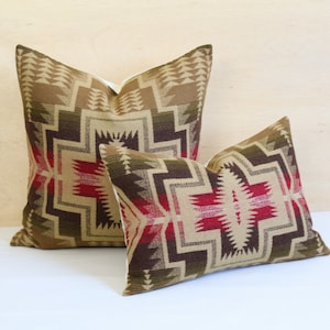 May include: Two decorative throw pillows featuring a geometric pattern in shades of brown, tan, and red. The pillows are crafted from woven fabric and have a soft, plush texture.