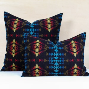May include: Two decorative throw pillows with a geometric pattern in shades of blue, red, yellow, and brown on a black background.