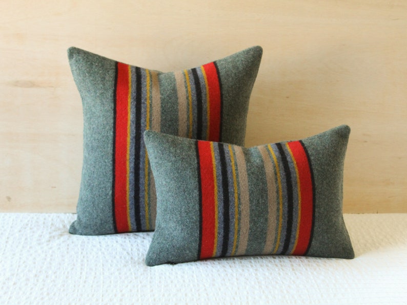 May include: Two decorative pillows with a striped pattern in shades of green, red, yellow, and black. The pillows are made of a soft, textured fabric.
