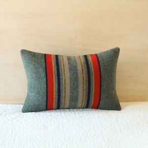 May include: A green and red striped throw pillow with a woven texture. The pillow is rectangular and has a subtle sheen.