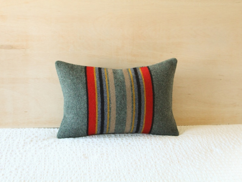 May include: A green and red striped throw pillow with a woven texture. The pillow is rectangular and has a subtle sheen.