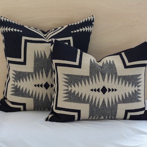 May include: Two decorative throw pillows with a geometric pattern in black and white on a white background.