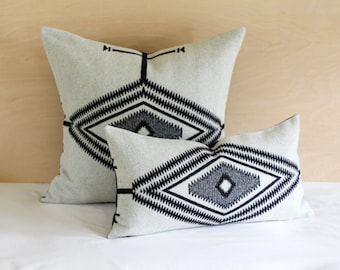 May include: Two decorative throw pillows with a geometric diamond pattern in black and white on a light grey background.
