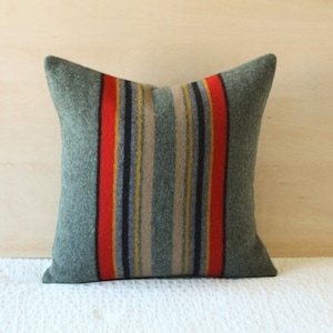 May include: A green and red striped throw pillow with a woven texture. The pillow is made of a soft, comfortable material and is perfect for adding a touch of style to any room.