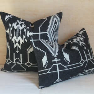 May include: Two black and white patterned throw pillows with a geometric design. The pillows are made of a soft, woven fabric.