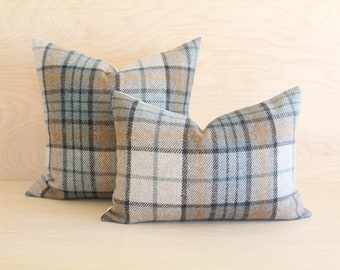 May include: Two decorative throw pillows with a plaid pattern in shades of grey, blue, and yellow. The pillows are made of a soft, textured fabric.