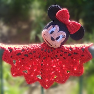 Puede incluir: Manta de bebé de ganchillo roja con una muñeca de ganchillo de Minnie Mouse unida. La muñeca tiene una nariz negra, ojos blancos y un lazo rojo.