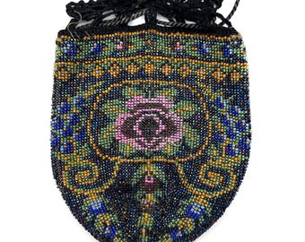 Puede incluir: Un bolso de cuentas vintage con cierre de cordón negro. El bolso presenta un patrón detallado de cuentas azules, verdes, amarillas y rosas. El diseño incluye elementos florales y geométricos.