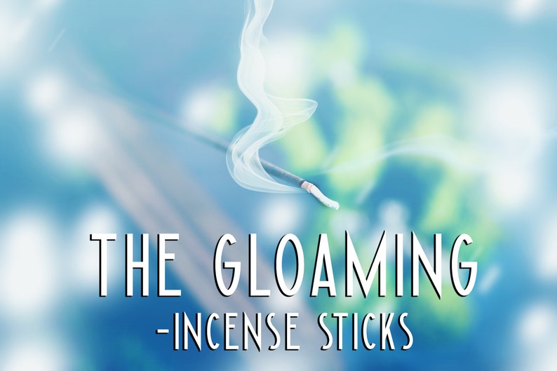 Pode incluir: Um pau de incenso branco com fuma&ccedil;a subindo sobre um fundo azul e verde desfocado. O texto "THE GLOAMING - INCENSE STICKS" est&aacute; abaixo do pau.