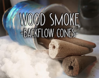 Może przedstawiać: Niebieski ceramiczny pojemnik przewrócony na bok, z którego wysypują się brązowe, stożkowe kadzidełka. Tekst WOOD SMOKE -BACKFLOW CONES- jest nałożony białą czcionką. Gęsta, biała, chmuropodobna para wydobywa się z podstawy kadzidełek.