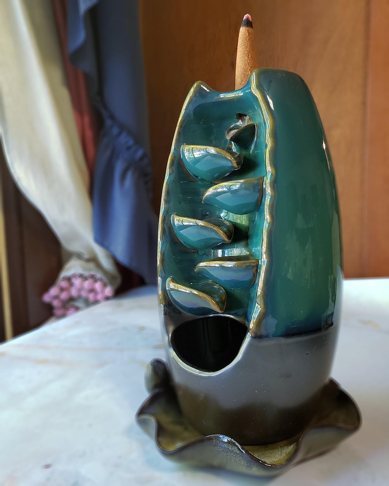 A ceramic fountain with a green and blue color scheme, featuring multiple tiers of water cascading down.