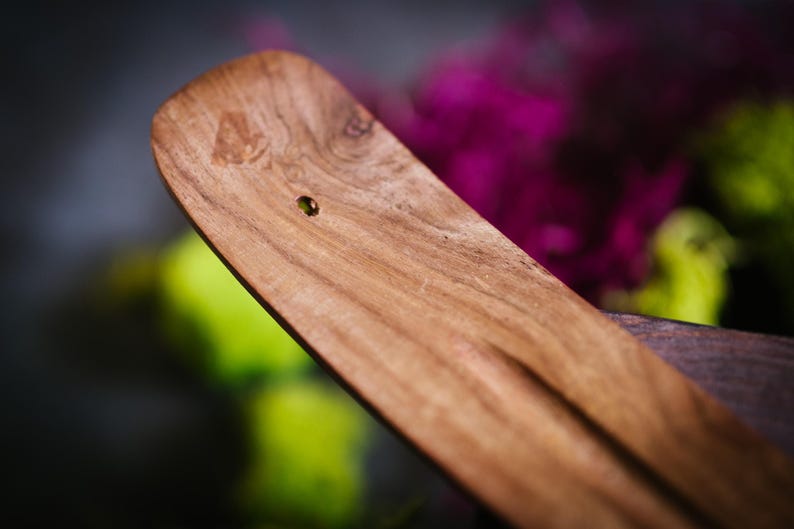 May include: A wooden incense burner with a small hole in the center. The burner is made of a light brown wood with a smooth finish.