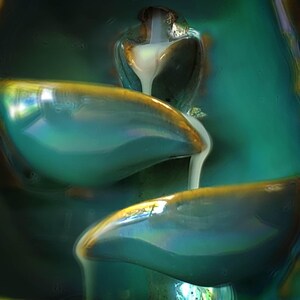 a close-up view of a glass sculpture with a flowing, cascading design. The sculpture has a greenish-blue hue and appears to be made of a translucent material, giving it a unique and artistic appearance.